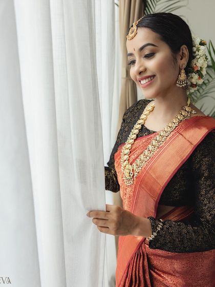 The bride's happy smile is captured perfectly as she looks out the window, bathed in soft, natural light.