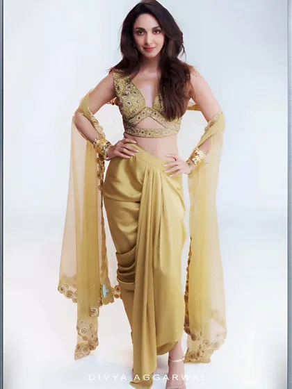 The radiant Kiara Advani embodies pure elegance in our golden Lydia Cape Set. This ensemble features a meticulously hand-embroidered blouse, a pre-draped dhoti-style skirt, and a flowing organza cape, making it a perfect choice for high-profile events.