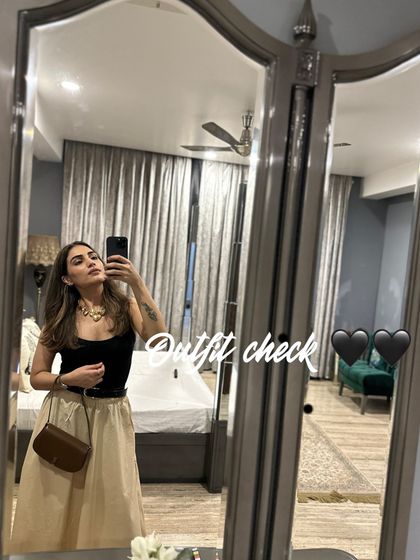 An outfit check in the mirror. A black top with a beige skirt is a classic combination that always looks polished.