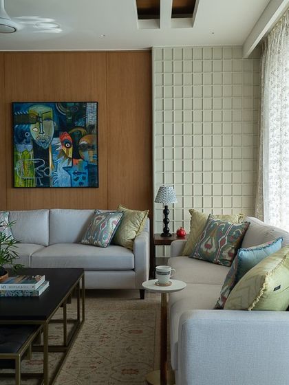 Another angle of the living room, showing the relationship between the warm oak veneer wall, the abstract art, and the textured white paneling. The overall feel is one of warmth and sophisticated comfort.