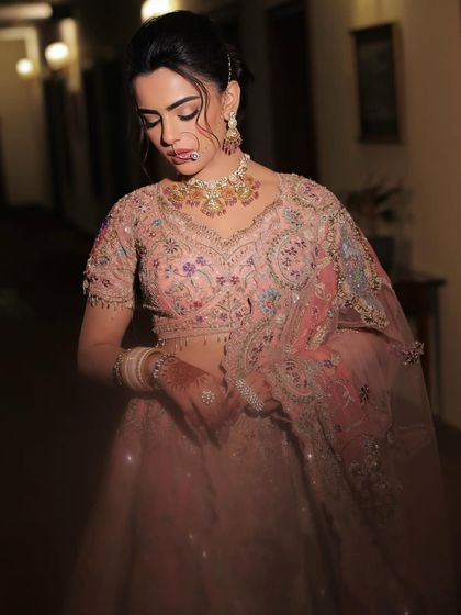 A full-body shot capturing the intricate details of the pastel lehenga. The soft, romantic makeup look ties everything together perfectly.