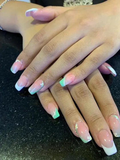 A fresh and delicate French manicure with alternating white and mint green tips. We added tiny, hand-painted white flowers for a subtle and beautiful detail on these square-shaped nail extensions.