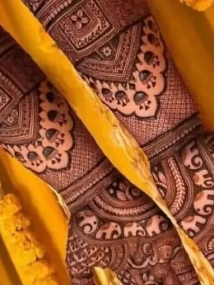 A close up view of a design rich with peacock motifs and traditional Indian patterns. The yellow marigold background adds to the festive wedding feel.