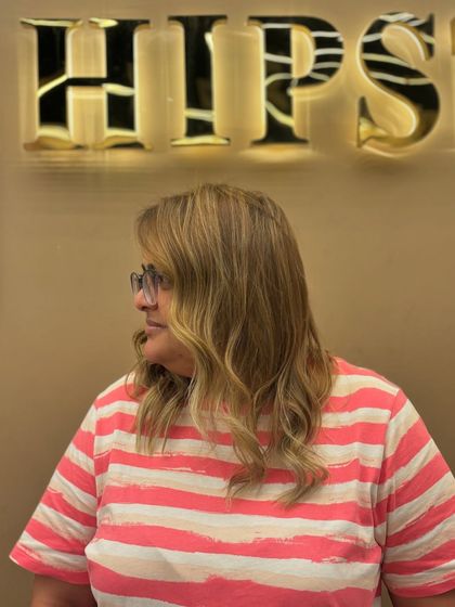 A side view of a client's hair after a color service. The soft waves and fresh color create a beautiful, modern look with plenty of movement.