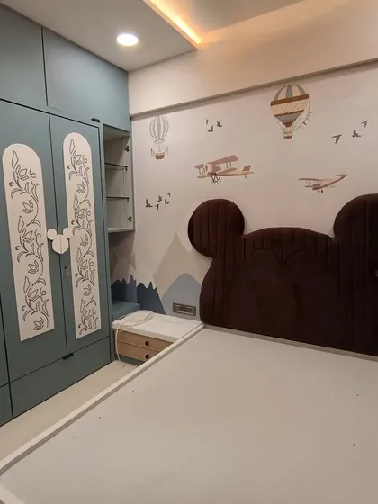 Designing a kid's room is always fun. This room features a Mickey Mouse-themed headboard, custom-painted wardrobes, and a whimsical wall decal with hot air balloons and airplanes.