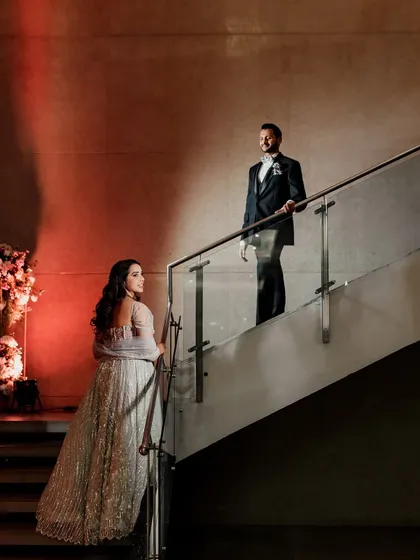 A dramatic and stylish portrait of the couple on a staircase, using lighting to create a moody and cinematic effect.