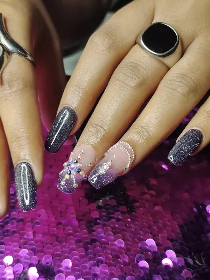 A close-up of the intricate 3D spider-like rhinestone design on a black glitter base.