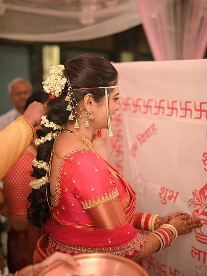 A detailed shot of the bride's back, highlighting the traditional hairstyle and the intricate design of her saree blouse.