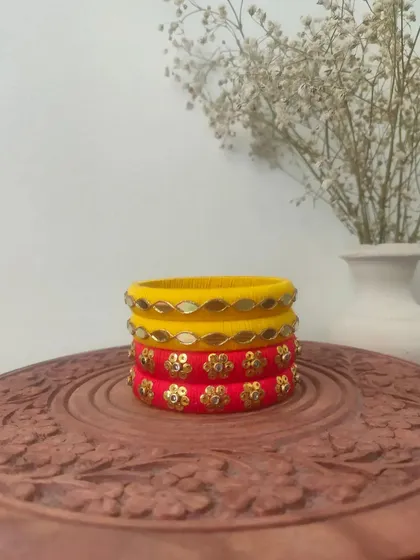 A bright and sunny set of handmade bangles in yellow and red. These are decorated with mirror work and floral sequin patterns, perfect for a Haldi or Mehendi function.