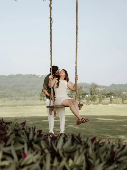 A sweet and playful moment of a couple on a swing in a beautiful park in Thailand. This image is full of charm and captures a simple, happy memory.