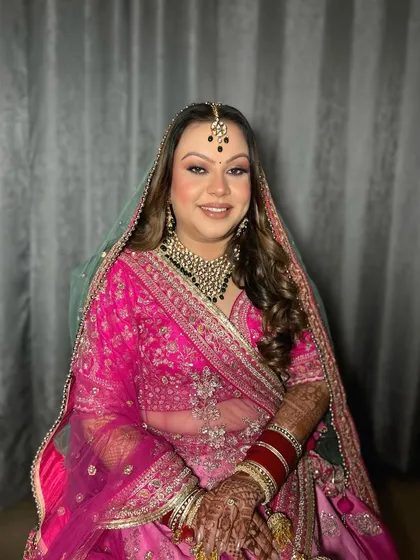 A beautiful client ready for her event in a stunning pink lehenga. The makeup is soft and bronzy, with a focus on her eyes.