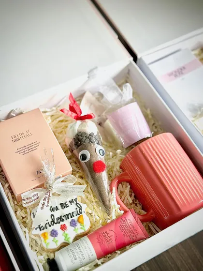 Inside the custom-printed box, I've included a fun hot chocolate kit, a "Will you be my Bridesmaid" cookie, a mini perfume, hand cream, and a cute mug. It’s a cozy and sweet proposal.