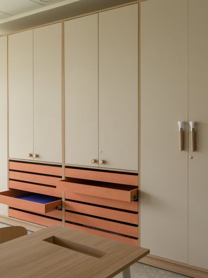 A close-up of the thoughtful storage design in an art or craft room. The multi-drawer cabinets with a pop of color inside are designed to keep countless supplies organized and easily accessible.