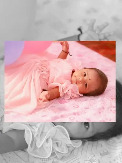 An artistic shot of a newborn baby in a beautiful pink dress, taken during her naming ceremony celebration.