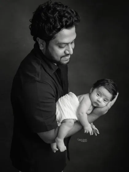A powerful black and white portrait of a father holding his newborn daughter in his arm.