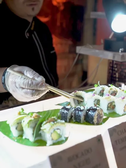 A chef carefully places a piece of sushi on a platter, showcasing the precision and care that goes into every dish.