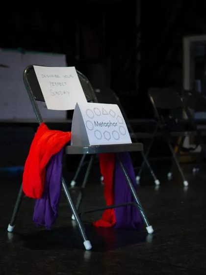 A chair draped with colorful scarves, set up for a "Metaphor" exercise during a workshop, showcasing the creative tools used in our space.