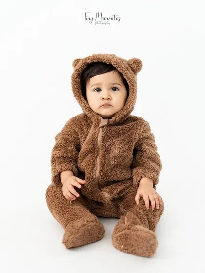 Sweeter than honey. This little one dressed in a fuzzy bear suit makes for an irresistibly cute and classic baby portrait against a clean white background.