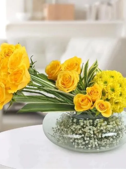 Perfect for a desk, coffee table, or reception area, this chic arrangement features sunny yellow roses and chrysanthemums in a modern glass bowl. It's a long-lasting design that brings a touch of sunshine indoors.