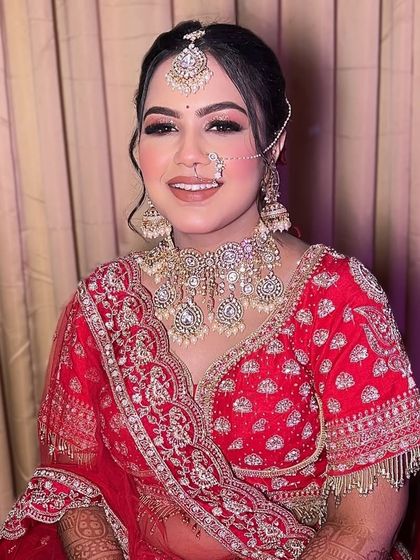 A happy and confident bride ready for her ceremony. We chose a classic look with defined eyes and a warm lip color to complement her red lehenga and intricate jewelry.