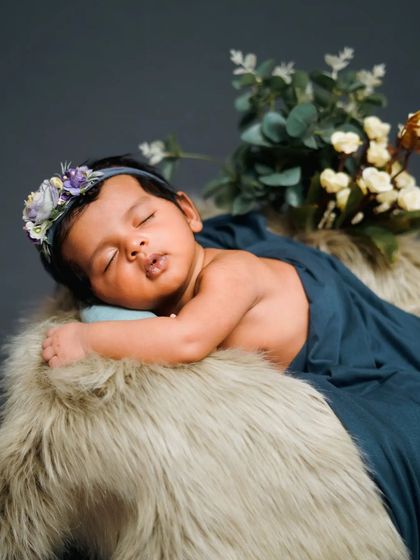 A classic and serene newborn pose on a soft fur rug, with a simple floral headband for a touch of elegance.