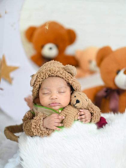 A sweet teddy bear theme where the baby is dressed in a fuzzy bear outfit, cuddling a smaller teddy. This is a classic and always adorable concept.