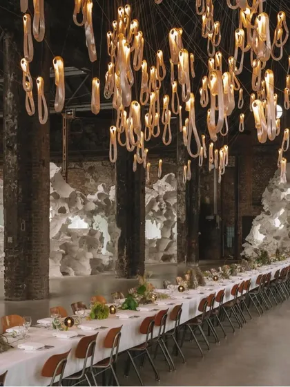 A closer view of the Bocci 87 chandelier over a dining setting. The stretching technique used to form these elegant loops is visible, and the tiny air bubbles within the glass create a beautiful pearlescent effect.