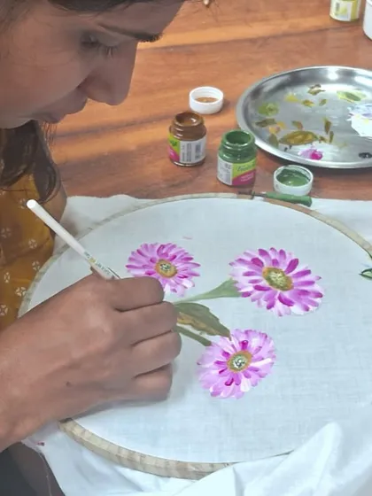 In our fabric painting workshops, you learn to transform simple cloth into wearable art. This student is using the one-stroke technique to paint delicate flowers, adding life to the fabric with every brushstroke.