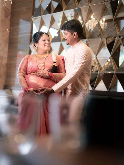 Another angle of the happy couple, framed through foreground elements to create a sense of intimacy. Their shared smile shows the joy of being surrounded by loved ones during this important milestone.