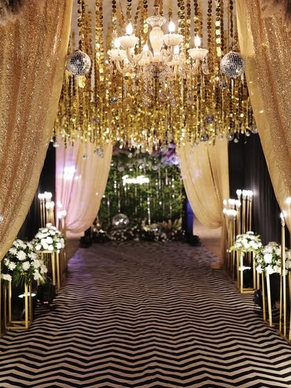 This grand entrance combines shimmering gold drapes with modern chevron flooring, creating a path of pure opulence.