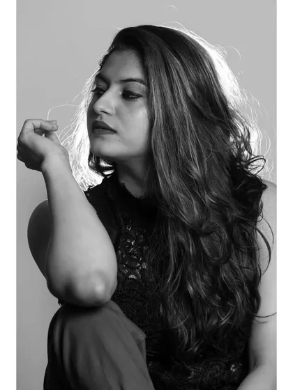 A pensive, looking-away profile shot in black and white. The use of shadow and light adds depth and mood to the portrait.