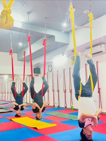 Synchronized inversions create a beautiful sense of unity in the class. Students hang in a supported headstand, enjoying the benefits together in our colorful studio.