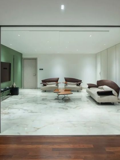 A modern living room enclosed by gridded glass sliding doors, allowing the space to be either open or private. The wooden flooring provides a warm contrast to the cool marble of the outer area.