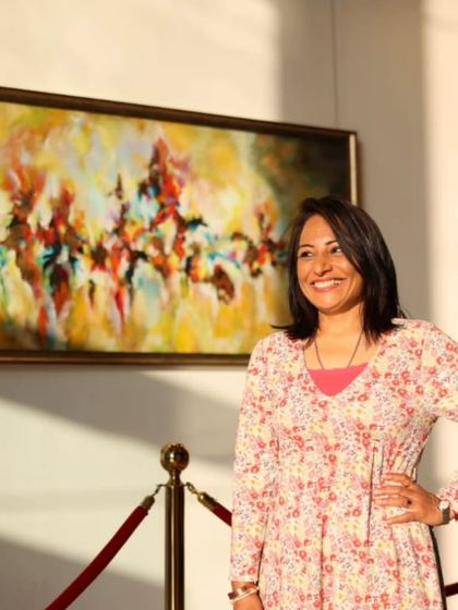 Artist Malika Vijay on the opening day of 'Nature's Symphony', posing proudly with her abstract landscape painting.