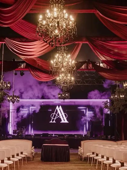The performance area under a ceiling of draped red fabric and hanging chandeliers. The monogram on the LED screen and dramatic smoke effects created a perfect stage for the couple's celebration.