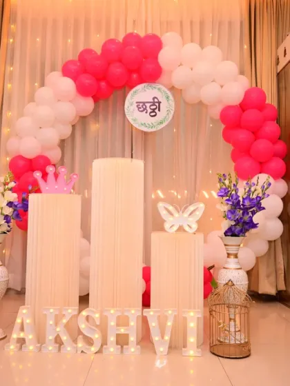 I handle decorations for traditional functions, like this Chhathi ceremony. The setup includes a pink and white balloon arch, marquee letters, and specific props to suit the cultural significance of the event.