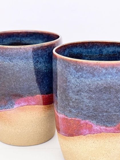 A close-up of the Celestial Dunes mugs, showing the beautiful interaction between the red, purple, and blue glazes.