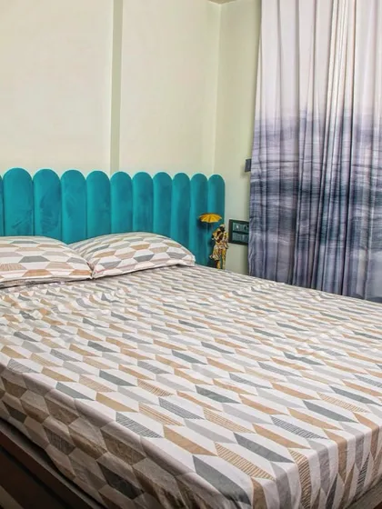 A pop of color with this vibrant teal scalloped headboard, which serves as a stunning focal point in this otherwise minimalist bedroom. The gradient curtains add a unique artistic touch.