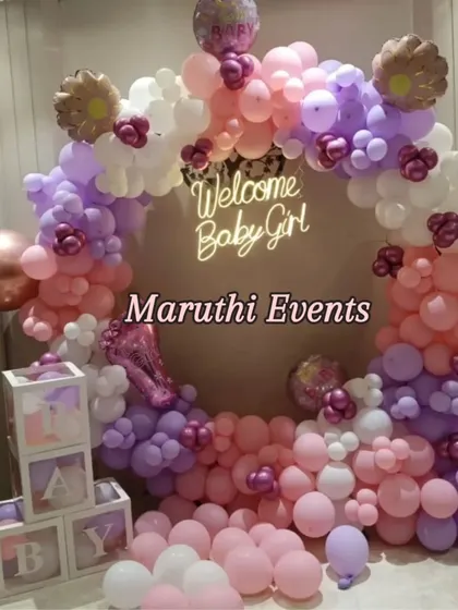 A beautiful and modern 'Welcome Baby Girl' decoration. This setup uses a circular balloon arch in pastel pink, purple, and white, a custom neon sign, and transparent 'BABY' blocks for a chic and memorable baby shower or homecoming.