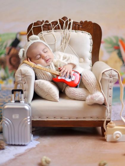 Ready for a beach nap. This adorable shot features a baby in a cozy knit outfit, ready to relax with his guitar after a day of fun in the sun.