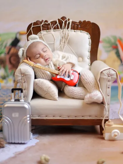 Ready for a beach nap. This adorable shot features a baby in a cozy knit outfit, ready to relax with his guitar after a day of fun in the sun.