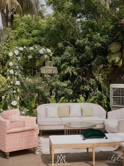 A comfortable and stylish lounge area set amidst the greenery, featuring pastel pink sofas and armchairs for guests to relax and enjoy the beautiful surroundings.