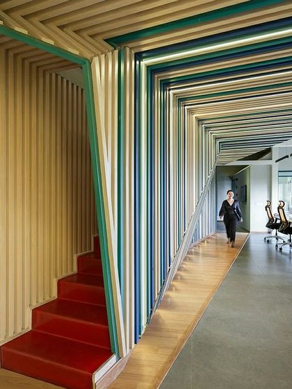 The 'red' stairwell in the Kadence Office is a bold, hollowed-out element that connects the two floors. It acts as a vibrant focal point, a streak of color that cuts through the space and guides movement.