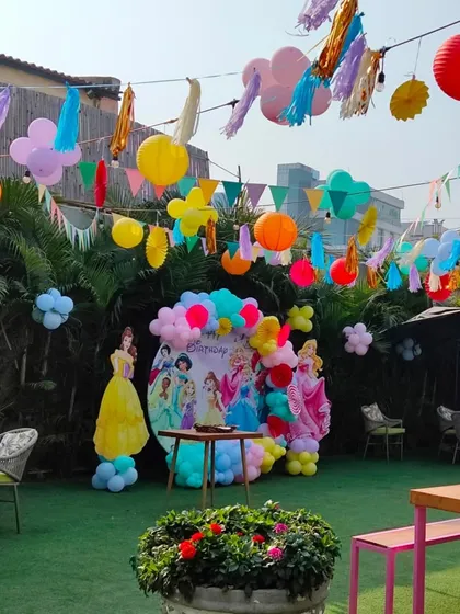 A beautiful outdoor setup for a princess-themed party, with colorful lanterns and banners hanging above the seating area.