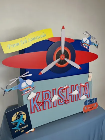 Adventure awaits! This travel-themed gift box for baby Krishna is ready for takeoff, complete with airplane and helicopter details, a personalized passport, and vintage-style luggage containing wonderful surprises.