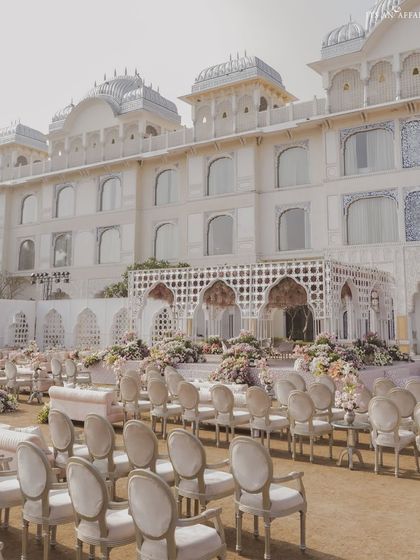 The grand scale of the wedding decor set against the palace hotel. The consistent use of white jali structures creates a cohesive and impressive visual impact for this destination wedding.