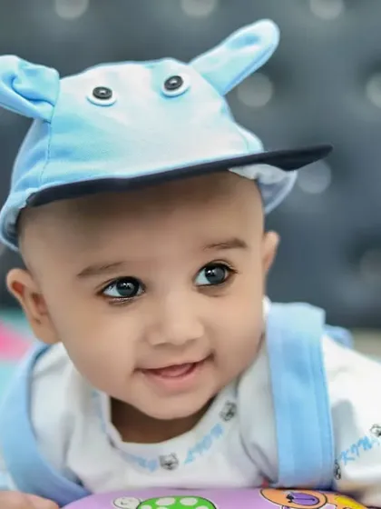 A close-up of a smiling baby boy wearing an adorable cap. Capturing these happy expressions is what makes baby photography so rewarding.