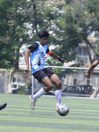 An U-15 player showing great technique and balance as he controls the ball mid-air during a competitive match. This is a testament to the technical skills honed during training.