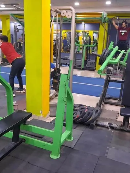 Members working on different goals in the same space. One person is doing a cable exercise for their back while another uses a plate-loaded machine for pull-ups, showing the variety of equipment available.