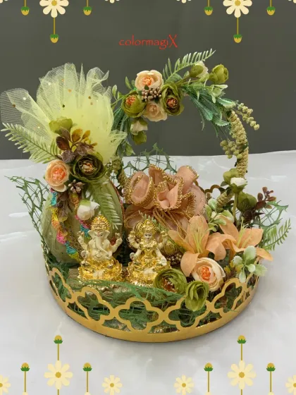 Gift blessings and prosperity with our divine Diwali basket. This ornate golden tray holds beautifully decorated pouches and idols of Lord Ganesha and Maa Lakshmi, surrounded by delicate flowers.